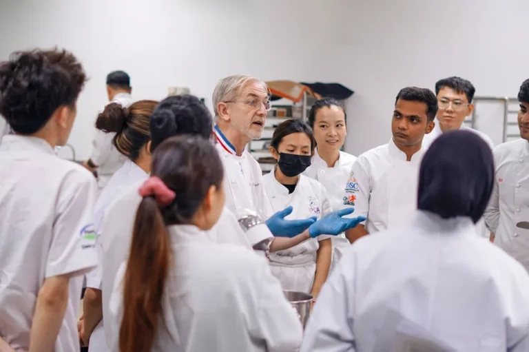 A visiting master chef explaining a technique to a class of APCA students